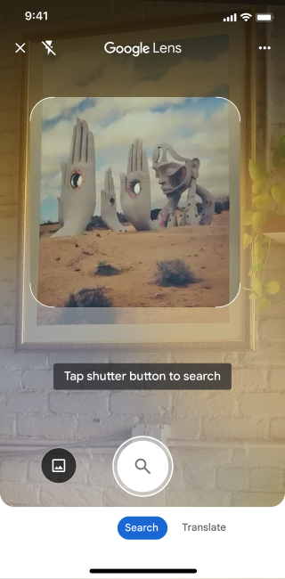 On a phone, the Google Lens app is open. A notification indicates the user can tap the shutter button to search an image of large stone hand sculptures in a desert.